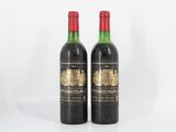 deux bouteilles de vin rouge posées l'une à côté de l'autre sur une surface blanche