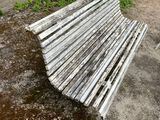 a broken wooden bench sitting in front of a brick building