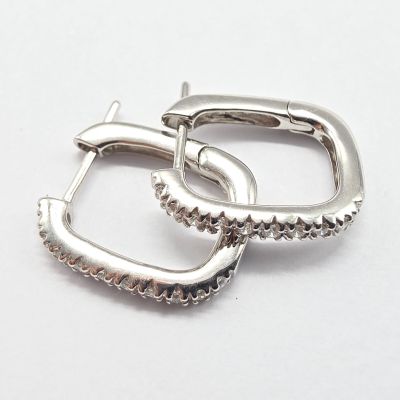 une paire de boucles d'oreilles créoles en argent sur fond blanc
