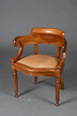 une chaise ancienne en bois, avec une assise et des accoudoirs en cuir beige