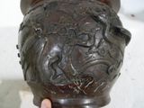 une main tenant un vase orné d’un motif
