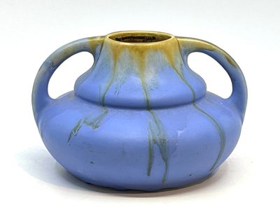 un vase bleu et jaune muni d'anses, posé sur une surface blanche