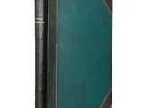 an old book with a green cover sitting on top of a white surface