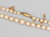 un gros plan sur un collier de perles muni d'un fermoir en or