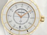 a close up of a watch on a white surface with gold accents