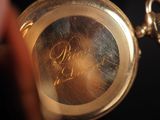 a close up of a gold pocket watch with writing on it