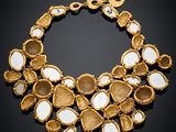 a close up of a gold and white necklace on a black surface