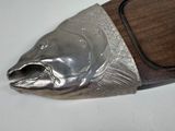 a silver fish on a wooden plaque on a white surface