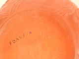 an orange vase with writing on it sitting on a table
