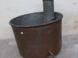 an old metal pot sitting on the ground next to a wall