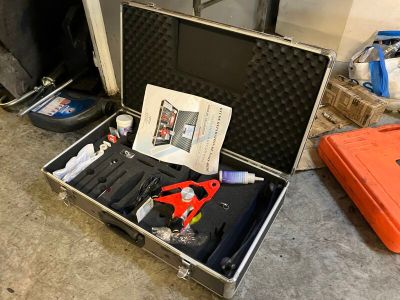 une valise contenant des outils, posée par terre