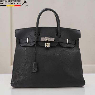 un sac à main en cuir noir posé sur une table blanche