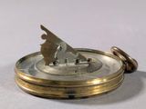 a close up of a pocket watch on a white surface