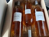 four bottles of maple syrup in a cardboard box on a table
