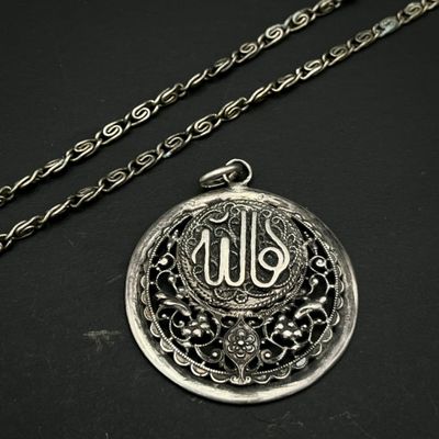 une photo d'un collier en argent orné d'un monogramme