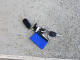 a blue bag with keys and a cell phone laying on the ground