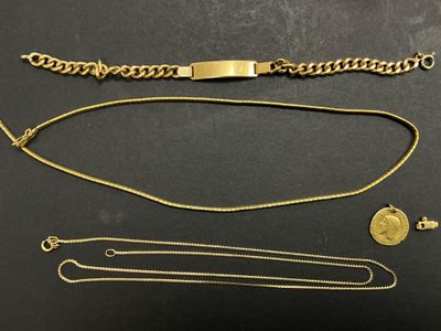 un gros plan sur un bracelet en or, une chaîne et une pièce de monnaie posés sur une table