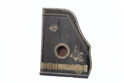 un vieil instrument de musique noir et doré sur fond blanc