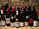 bottles of wine are lined up on a table in front of a stone wall