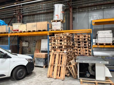 une camionnette blanche garée dans un entrepôt, à côté de palettes de bois