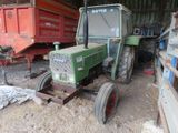 a green tractor that is parked in the dirt