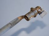 a rusted pipe with a metal handle and a tag attached to it