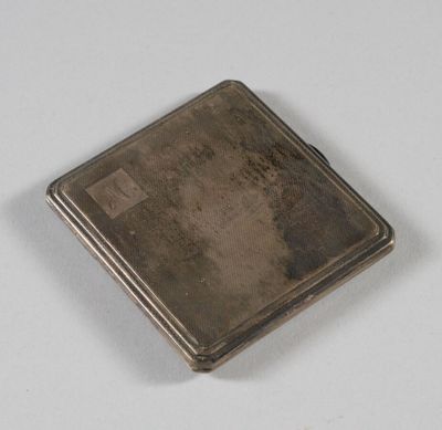 un étui à cigarettes ancien en argent posé sur une surface blanche