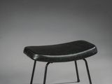 une photo en noir et blanc représentant un petit tabouret posé sur une surface blanche