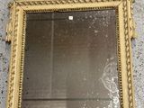 miroir à cadre doré accroché au mur, orné d'un motif représentant un oiseau et des feuilles