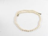collier de perles avec un fermoir en or sur fond blanc