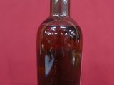 une bouteille en verre brun avec un bouchon argenté, posée sur un fond rose