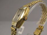 une photo d'une montre en or posée sur un socle transparent