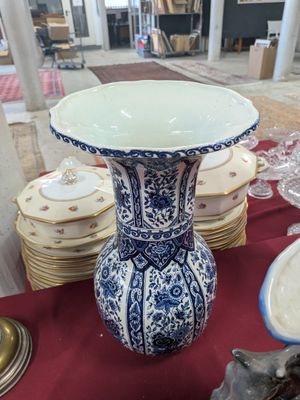 a blue and white vase sitting on a table with plates