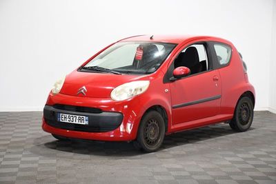 une voiture rouge de marque Citrole garée sur un sol à damier dans un garage
