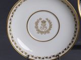 deux assiettes ornées de bordures dorées et d’un monogramme