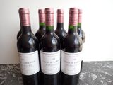 four bottles of red wine are lined up on a table
