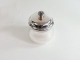 a small silver container with a lid on a white surface