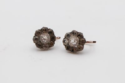 une paire de boucles d'oreilles clous en forme de losange, marron et blanches, posées sur un fond blanc