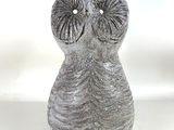 a gray vase with an owl face on it