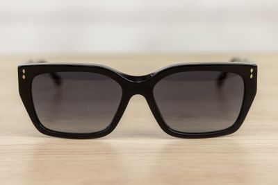 black sunglasses on a wooden table with a white wall in the background