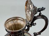 a silver pitcher that is sitting on a table