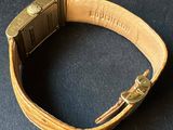 an image of a gold watch with a leather band on a black surface