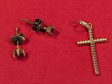 deux croix en or et une paire de boucles d'oreilles à clous sur un fond rouge