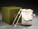 une tasse en argent contenant une cuillère, posée à côté d'une boîte verte