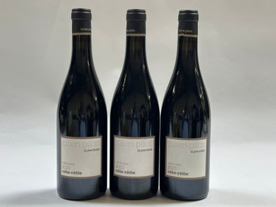 trois bouteilles de vin rouge sont posées sur une surface blanche