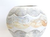 a white vase with a design on it on a white surface