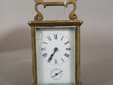a small brass clock with roman numerals on the face
