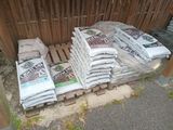 many bags of cement sitting on a pallet in front of a fence