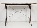 an old iron table with a marble top on a white floor