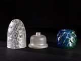 three different colored glass vases sitting on top of a black surface